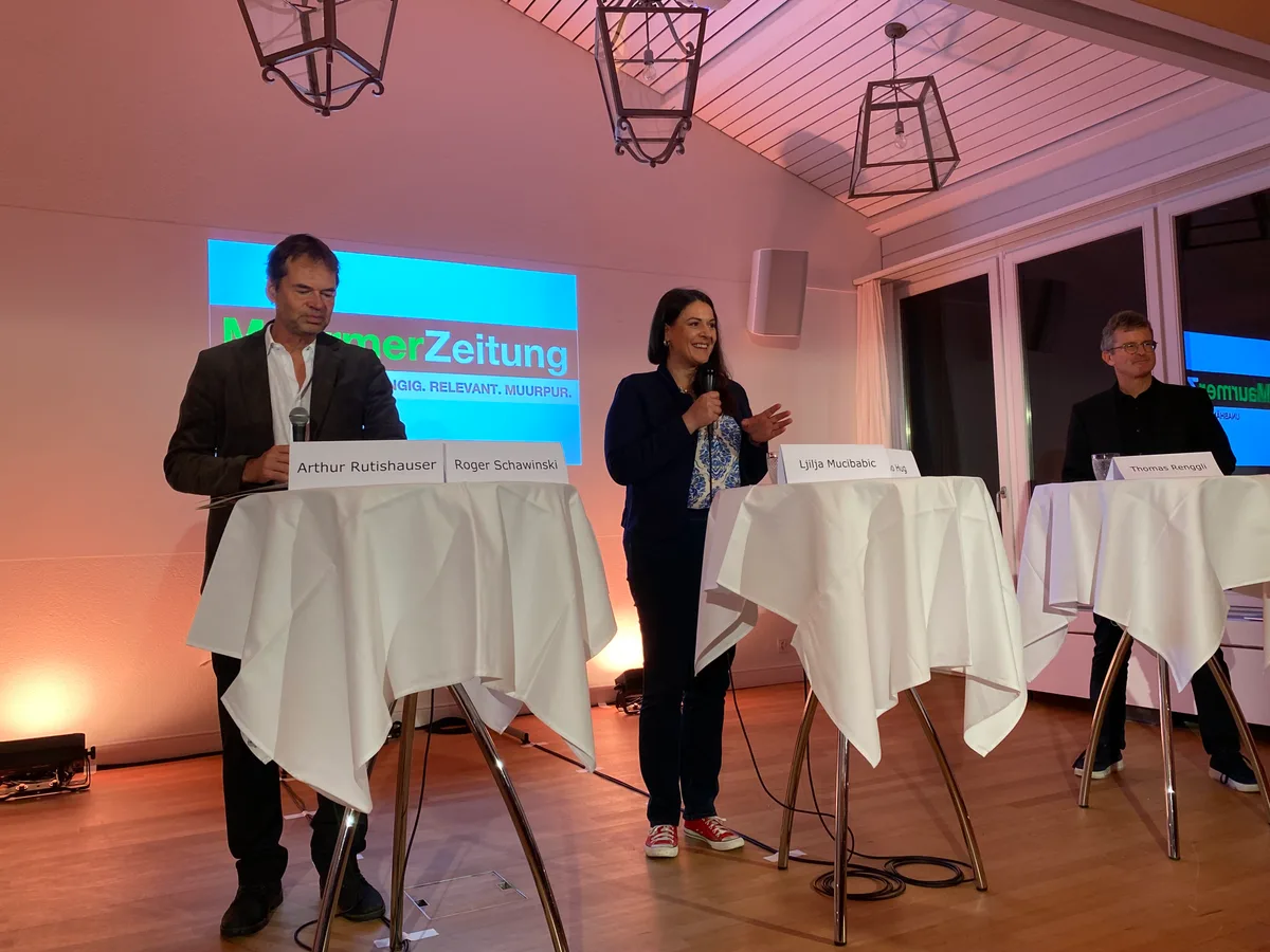 Menschen stehen hinter Stehpulten und führen eine Podiumsdiskussion.